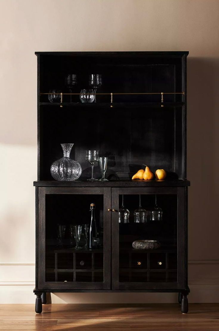 a black china cabinet with glass doors and gold trimmings on the bottom shelf