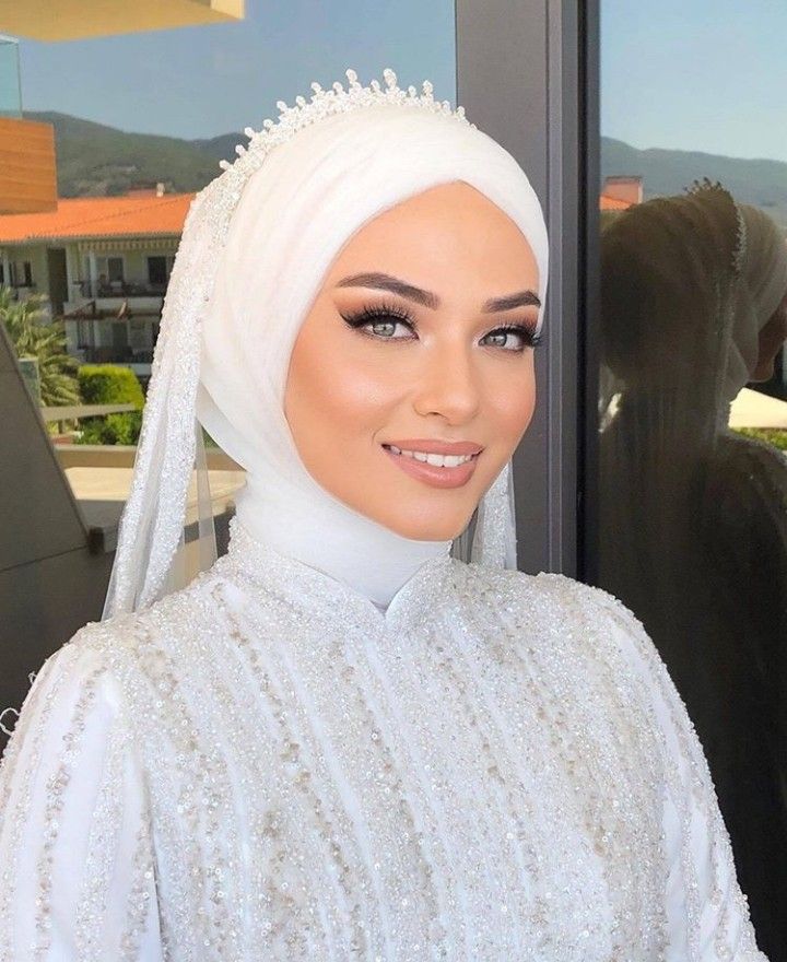 a woman wearing a white hijab with pearls on her head and veil over her head