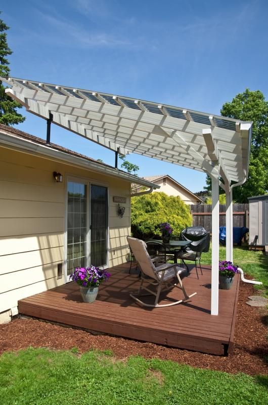 a backyard with a deck, chairs and an awning over the back yard area