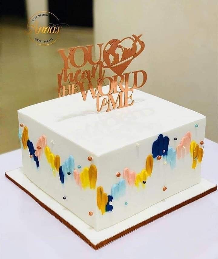 a white cake with gold lettering on top and colorful paint splatters all over it