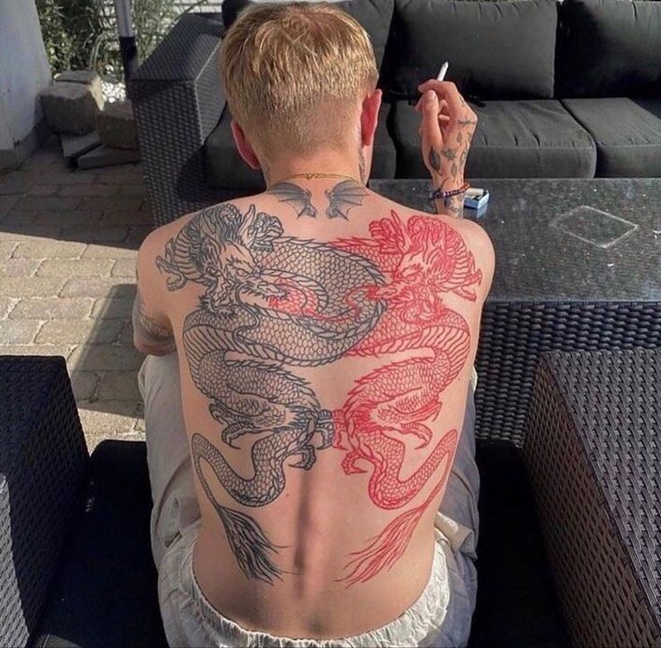 a man sitting on top of a couch next to a table with tattoos on his back