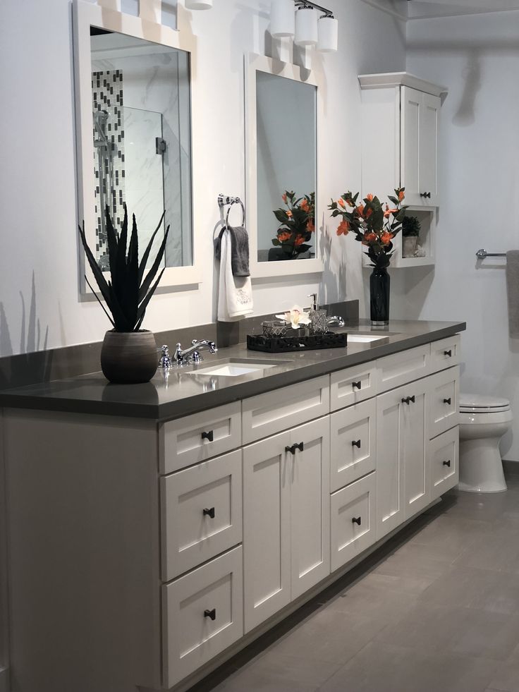 a bathroom with two sinks, mirrors and flowers in vases on the counter top