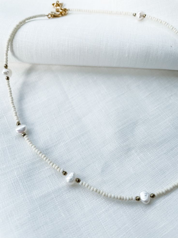 "Ivory seed beads with natural pearls and 3mm faceted hematite spacers. Necklace had lobster clasp closure with 2\" adjustable chain. Each piece is designed and handmade in Brooklyn. After visiting the Notre Maison orphanage in 2015, I fell in love with the children and knew I wanted to help sponsor them. That's what started this shop. Every purchase helps us sponsor 5 children at the orphanage that we follow up with and visit over the summers. Join our Ubuntu family so that together we can be t White Pearl Jewelry With Oval Beads, Handmade Adjustable Cream Pearl Necklace, Adjustable Handmade Cream Pearl Necklace, Cream Beaded Necklace With Round Beads, Pearl White Beaded Necklaces With Round Beads, Pearl Drop Beaded Necklaces With Round Beads, White Pearl Necklace With Oval Beads, White Pearl Jewelry With Faceted Beads, Adjustable Cream Beaded Pearl Necklace