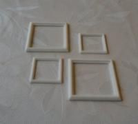 four white square frames sitting on top of a tablecloth covered table next to each other