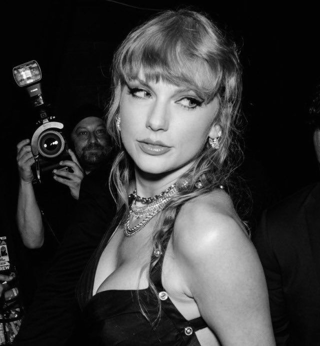 a woman in a black dress is holding a camera