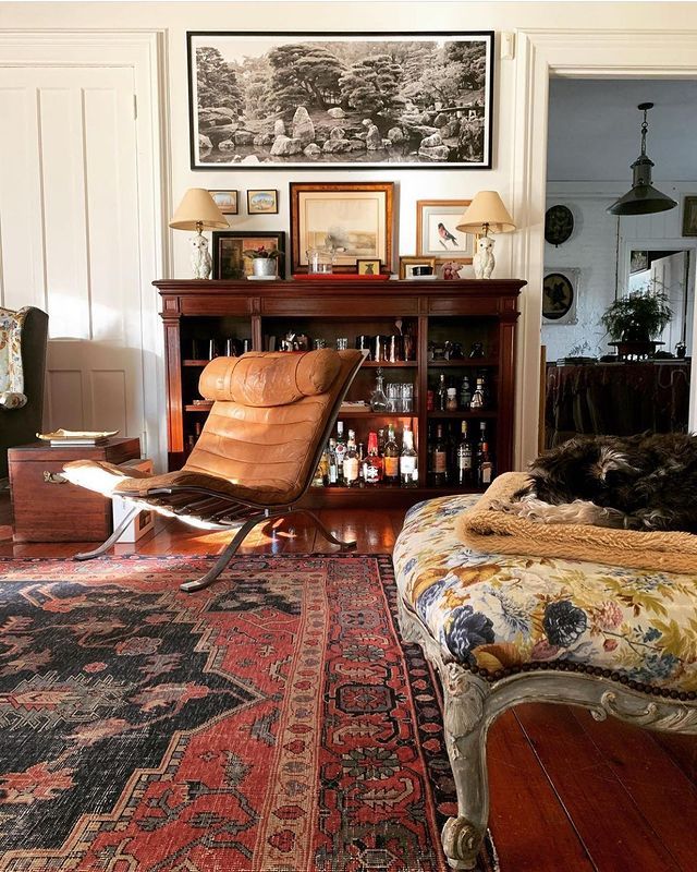 a living room filled with furniture and a fire place next to a book shelf full of bottles