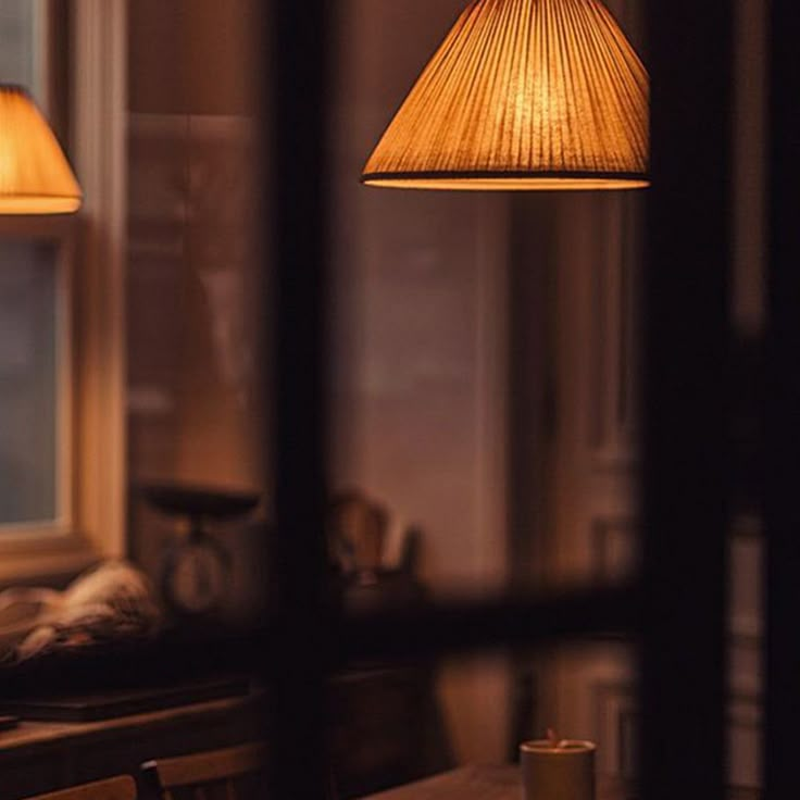 two lamps that are on top of a wooden table in front of a window with a view of the outside