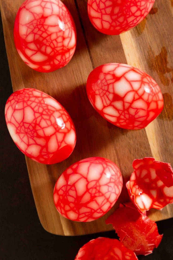 some red eggs are sitting on a cutting board