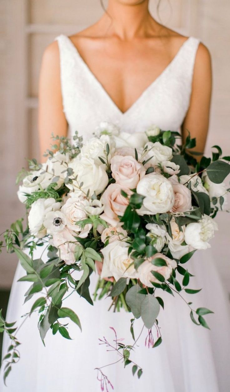 a bride holding a bouquet of white and pink flowers