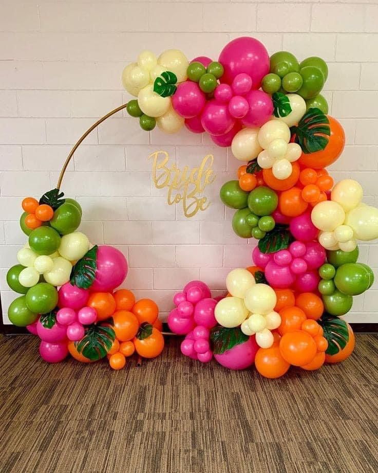 the balloon arch is decorated with oranges, pinks and green