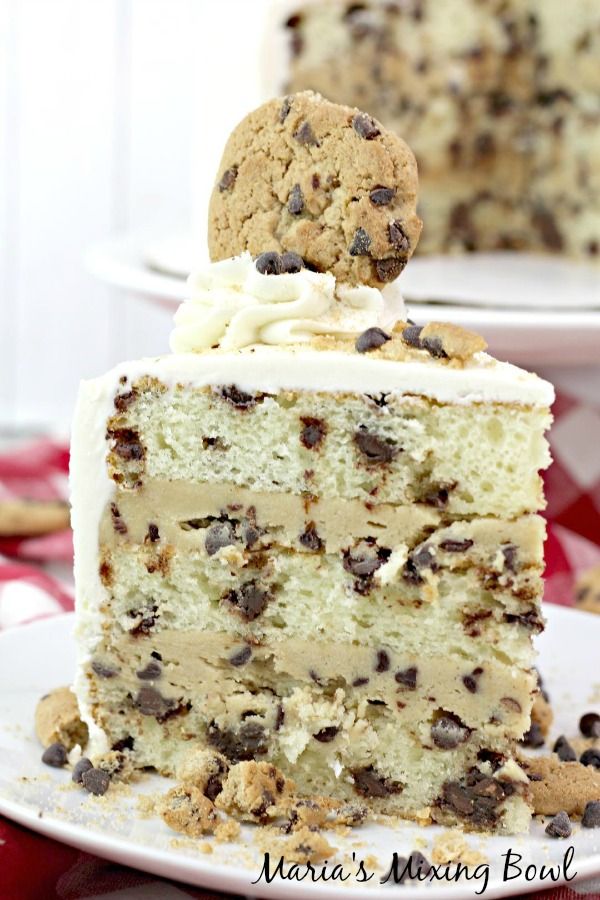 a slice of cake with white frosting and chocolate chip cookies on top is shown