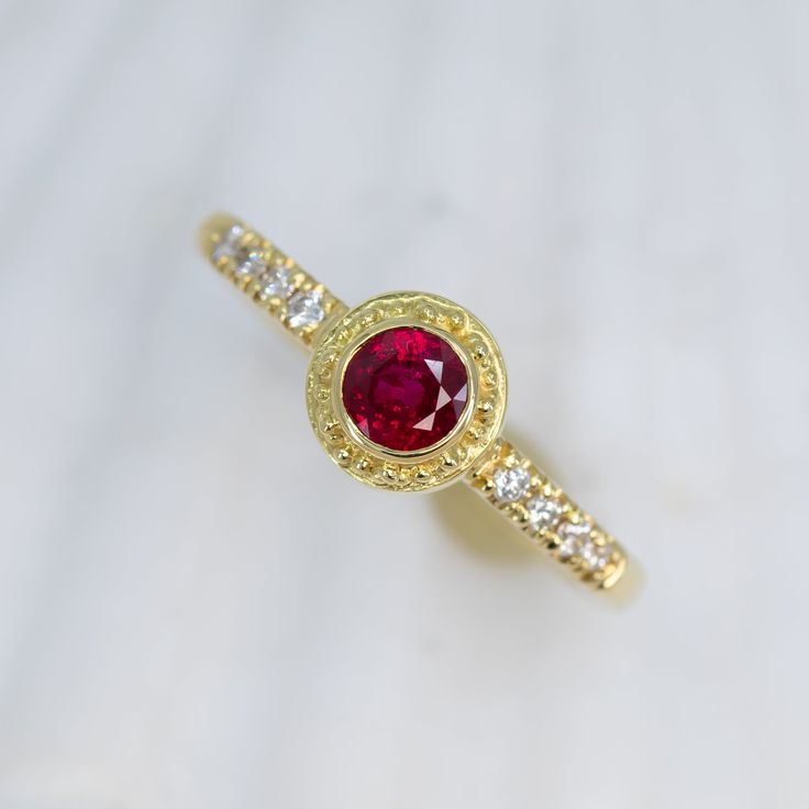 Treat yourself to an exquisite adornment handcrafted in 18K granulated gold, showcasing a stunning ruby and glittering diamonds, to add a hint of sophistication and charm to any outfit. The classic simplicity of this Ruby & Diamond Classical Ring will add an elegant allure to your jewelry collection. Featuring a dazzling 0.58ct ruby accented with 0.1cttw of 1.5mm VS/GH diamonds. Size 6, but each ring comes with free sizing and FREE SHIPPING! Watch a video of this ring being made HERE Unsure what Ruby Ring With Pave Setting And Diamond, Ruby Ring With Diamond Pavé Setting, Formal Yellow Gold Ruby Ring With Pave Setting, Ruby Rings With Single Cut Diamonds, Ruby Rings With Pave Setting, Ruby Rings With Round Cut Single Diamonds, Elegant Yellow Gold Ruby Ring With Pave Setting, Luxury Yellow Gold Ruby Birthstone Ring, Gold Ruby Rings With Pave Setting