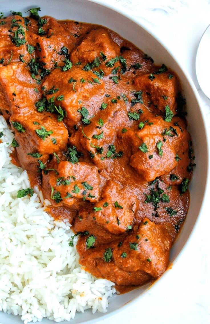 a white bowl filled with rice and meat covered in sauce