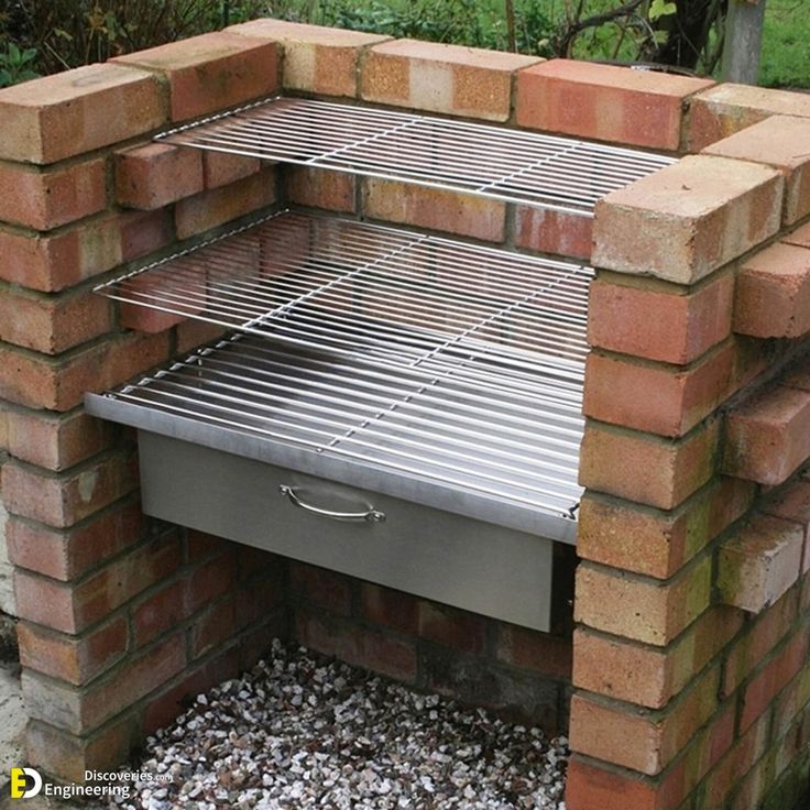 an outdoor bbq grill built into the side of a brick wall with gravel around it