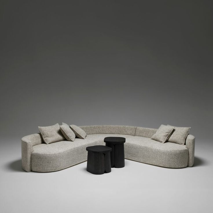 a couch and two stools in front of a gray wall