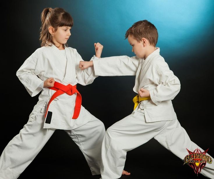 two young children in karate uniforms standing on one leg and holding their hands up to the other