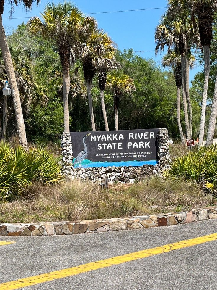 the sign for myakka river state park in front of some trees and bushes