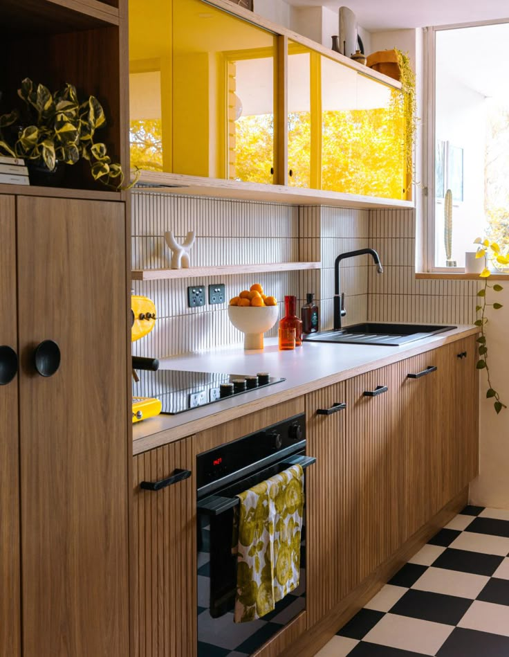 a kitchen with black and white checkered flooring next to a yellow cabinet door