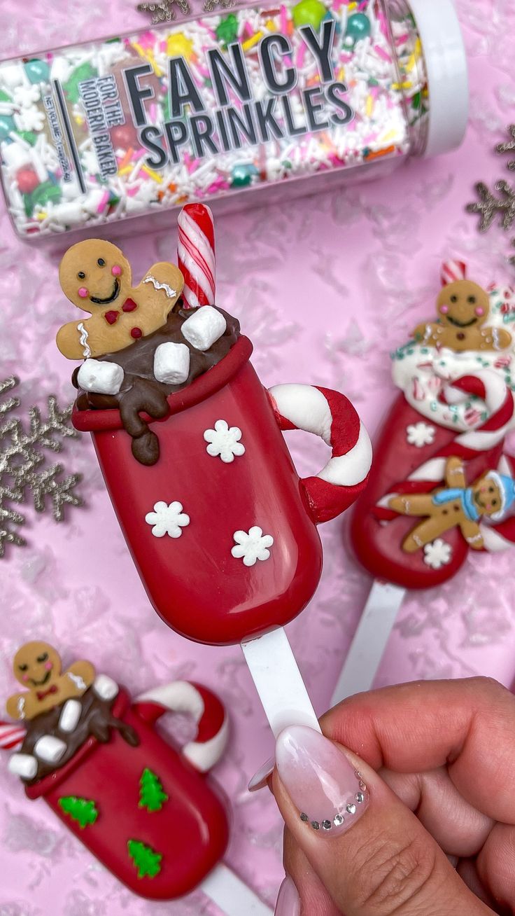 a person is holding a popsicle decorated with gingerbreads and other holiday decorations