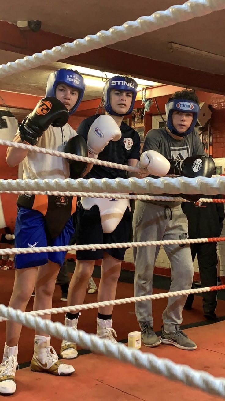 three young men standing next to each other in a boxing ring