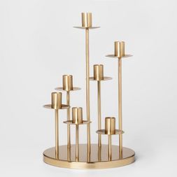 a gold candle holder with six candles in it on a white background, there is a circular metal stand that holds five candles