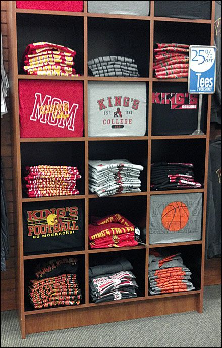 a wooden shelf filled with shirts and t - shirts