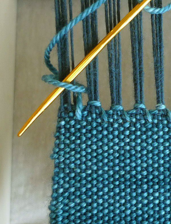 a close up of a blue piece of cloth with a knitting needle