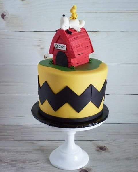 a yellow and black cake with a red house on top that is decorated to look like a doghouse