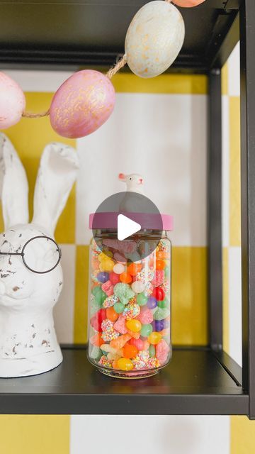 a glass jar filled with candy sitting on top of a shelf next to a bunny head