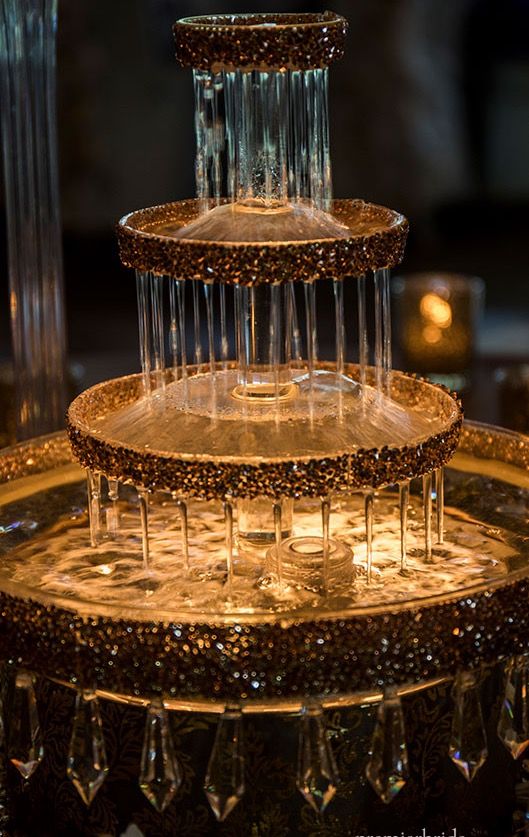 three tiered glass cake stand with candles in the background and lights on each side