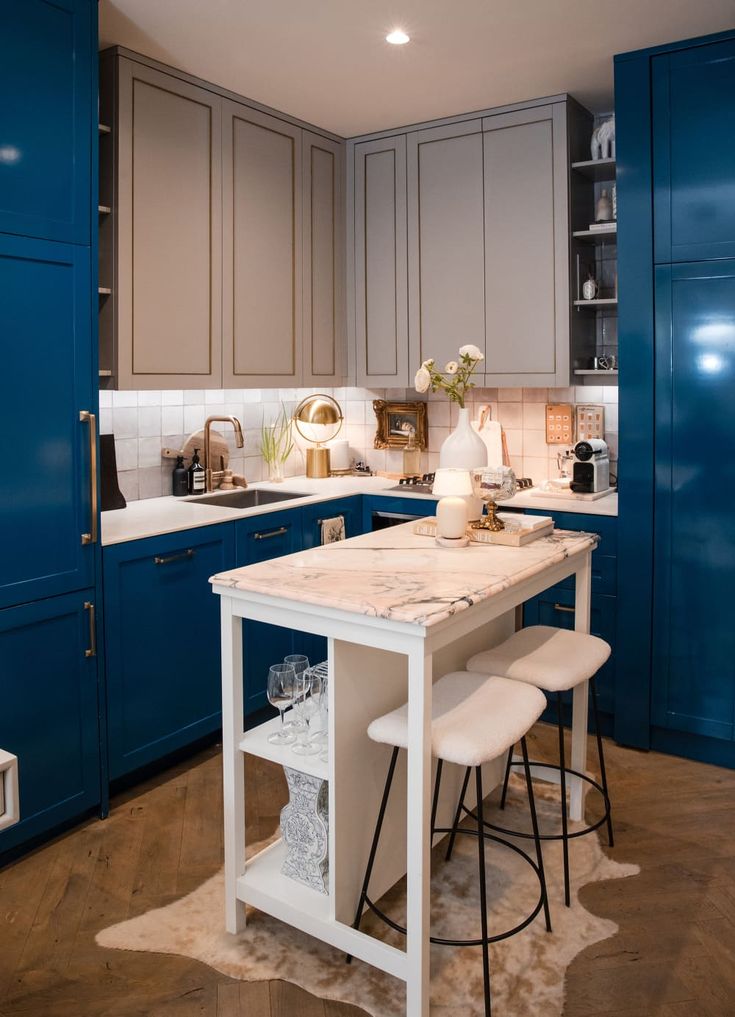 an image of a kitchen with blue cabinets and white stools on the counter top