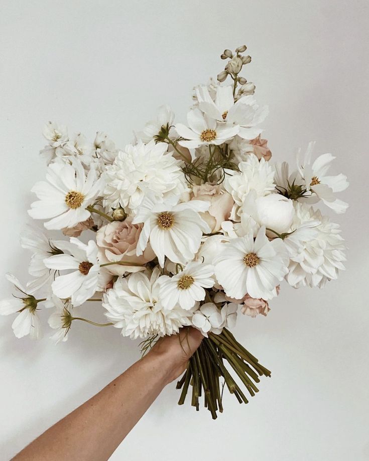 a hand holding a bouquet of white flowers