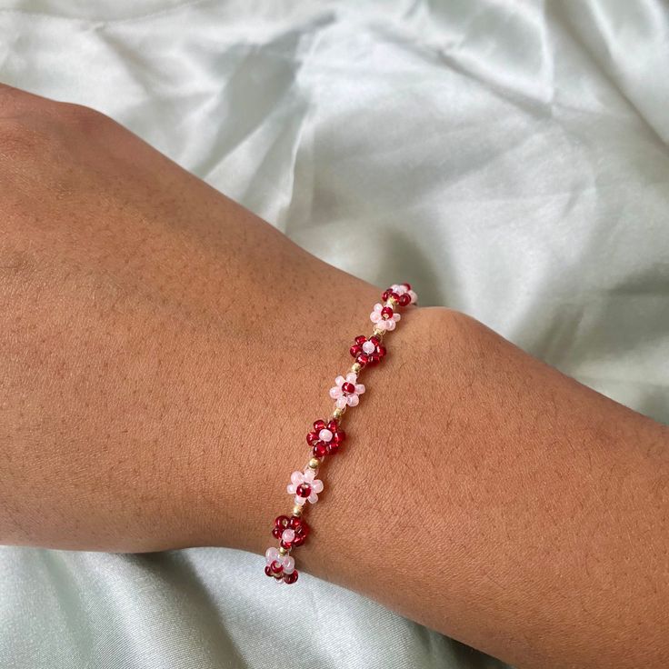 a woman's arm with a red and white beaded bracelet on top of it