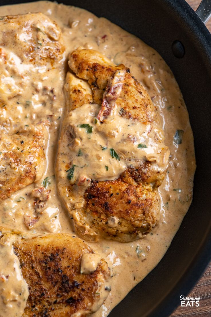 chicken with gravy in a skillet on top of a wooden table,