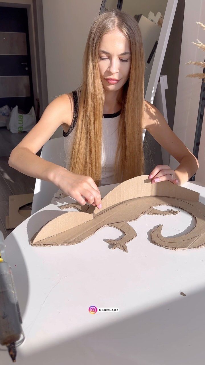 a woman is making a cardboard mask out of cardboard