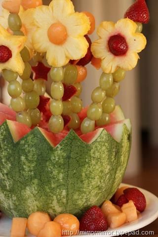 a watermelon bowl filled with fruit and flowers