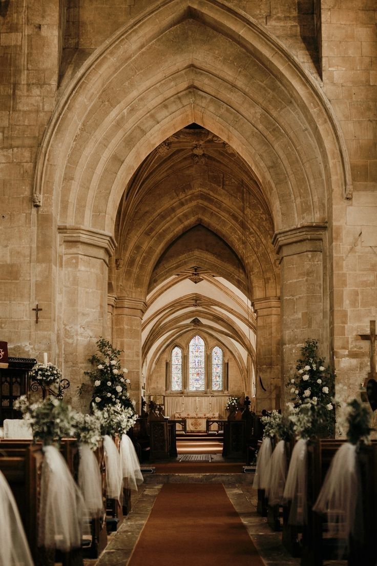 a church filled with lots of pews covered in white tulle and flower arrangements