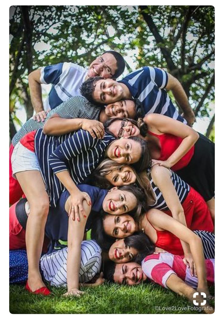 a group of people that are standing together in the grass with their heads on top of each other