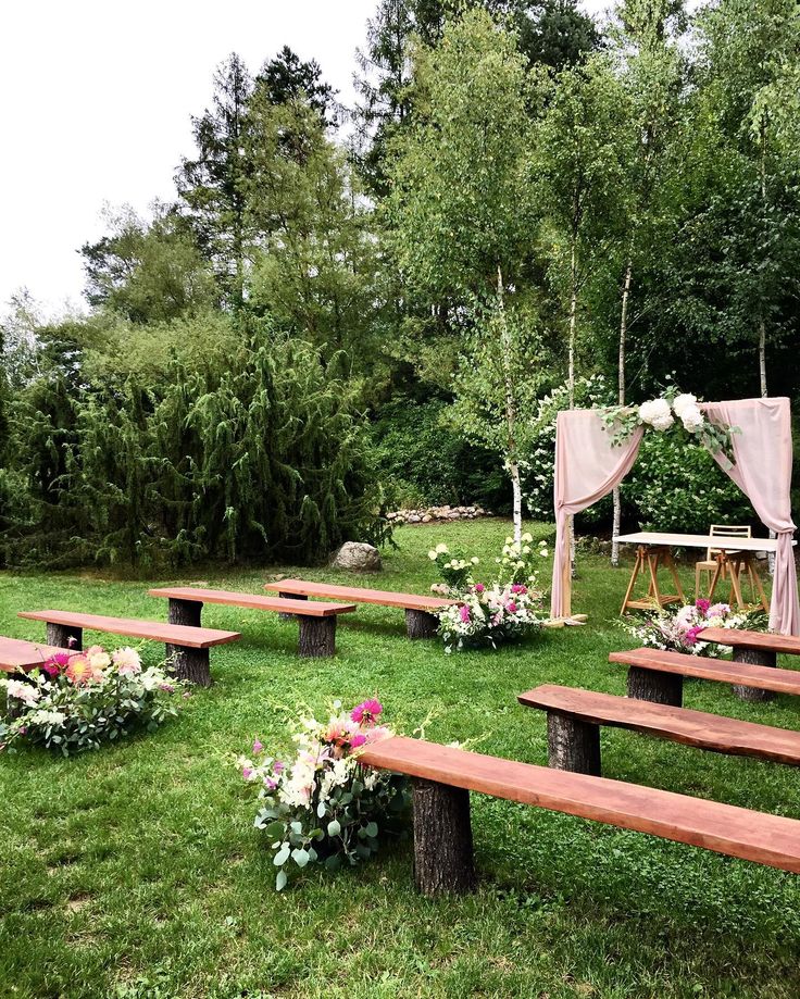 an outdoor ceremony setup with wooden benches and flowers