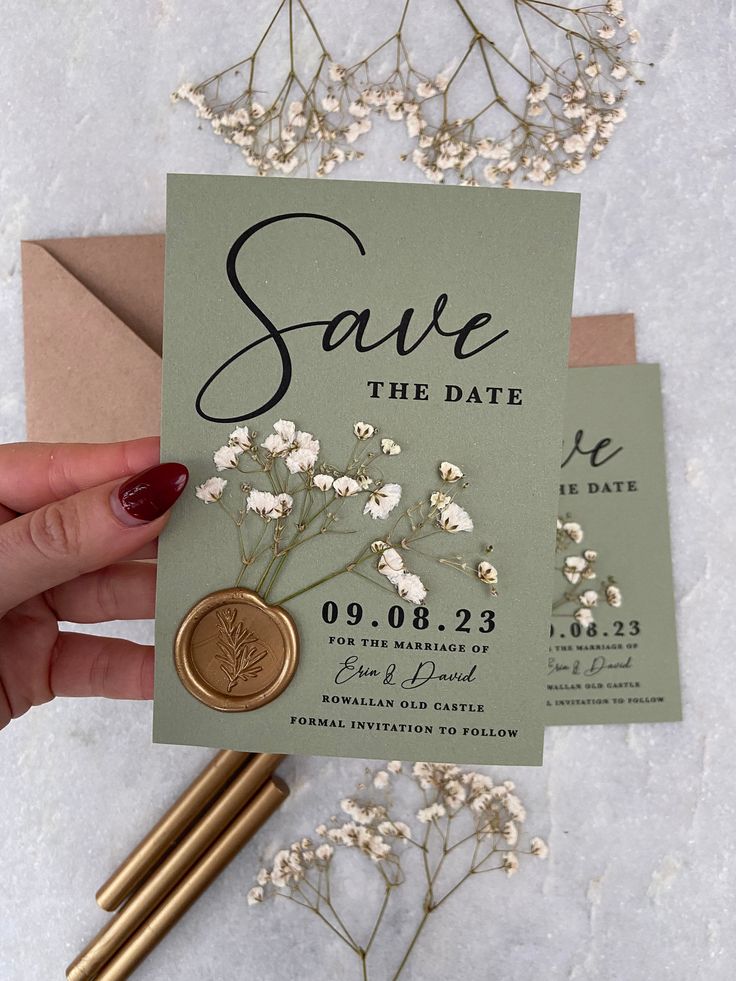 save the date card with wax stamp and flowers on it next to some envelopes