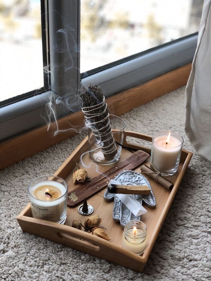 a tray with candles and other items sitting on the floor next to a window sill