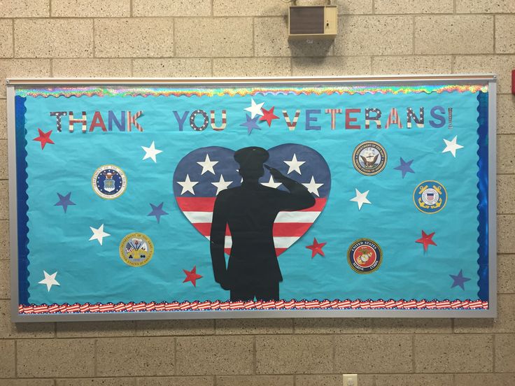 a man salutes his hat in front of a thank you veterans banner on the wall