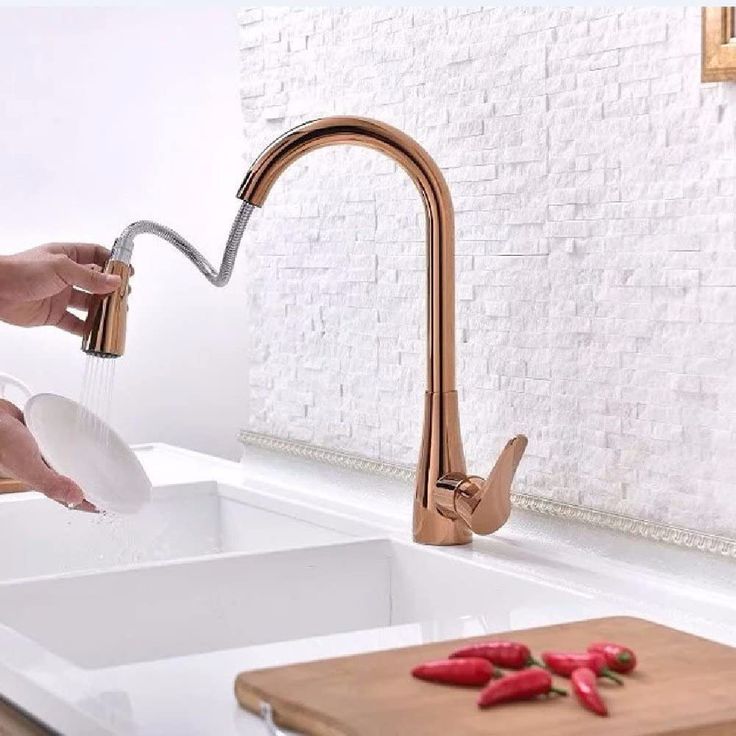 a person is pouring water into a kitchen sink with peppers on the counter and cutting board next to it