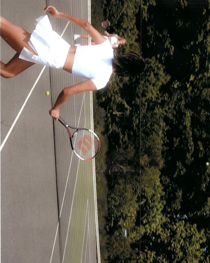 a female tennis player in action on the court with her racquet raised up