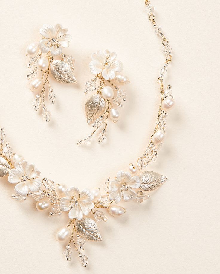 a necklace and earring set with pearls, leaves and beads on a white background