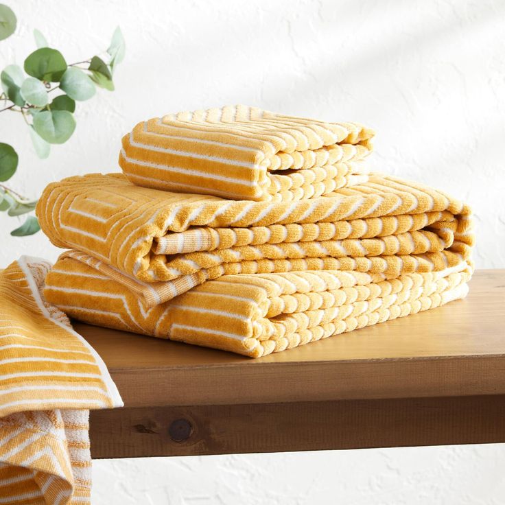 a stack of yellow towels sitting on top of a wooden table