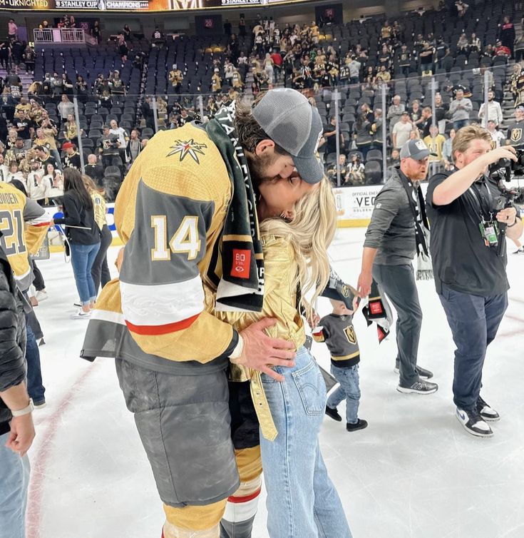 a man and woman kissing on the ice in front of an arena full of people