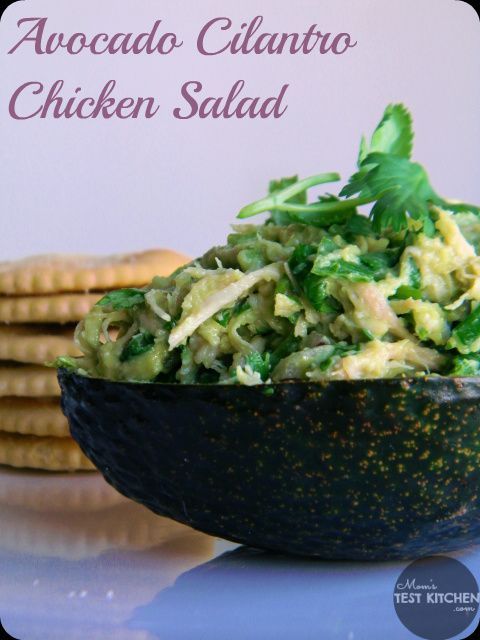 a bowl filled with chicken salad next to crackers on a plate and the words, avocado cilantro chicken salad