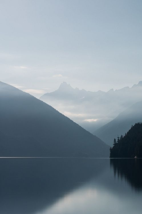 a lake with mountains in the background and fog on the water, as far as the eye can see