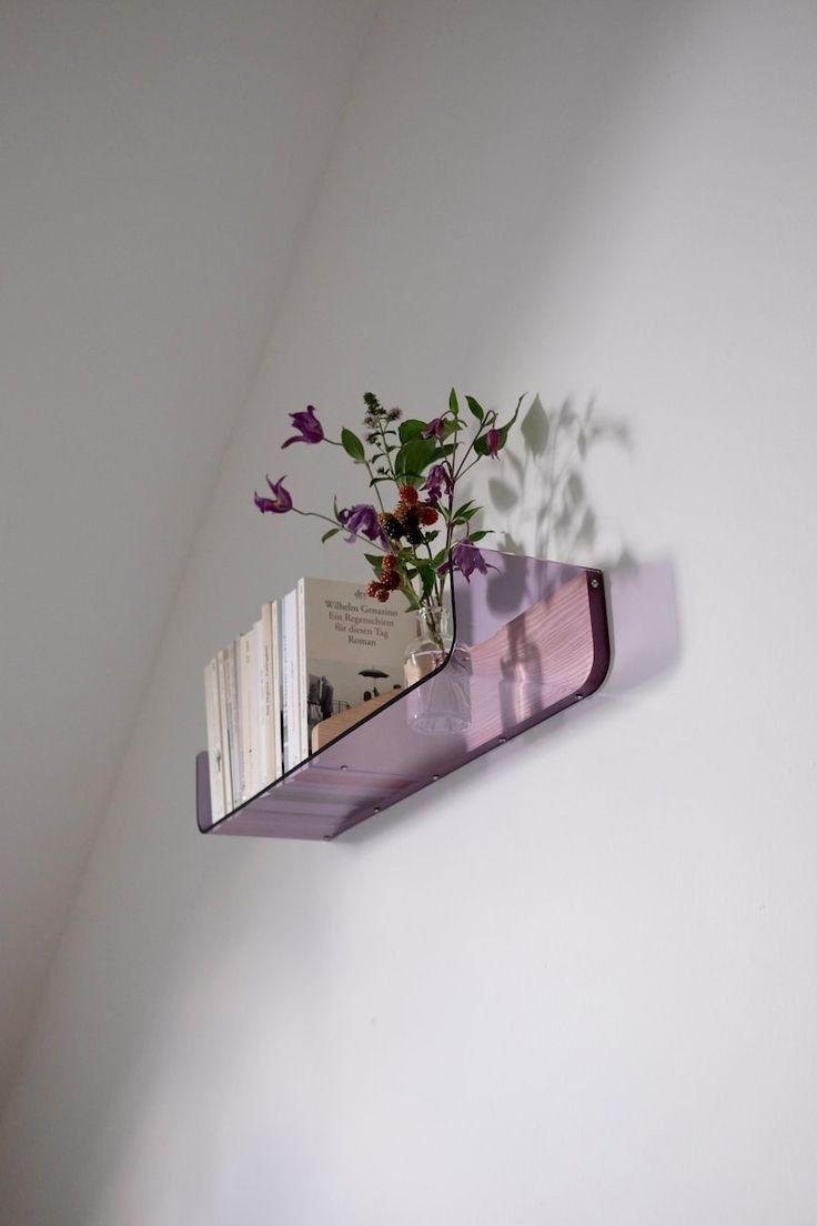 a purple shelf with books and flowers on it